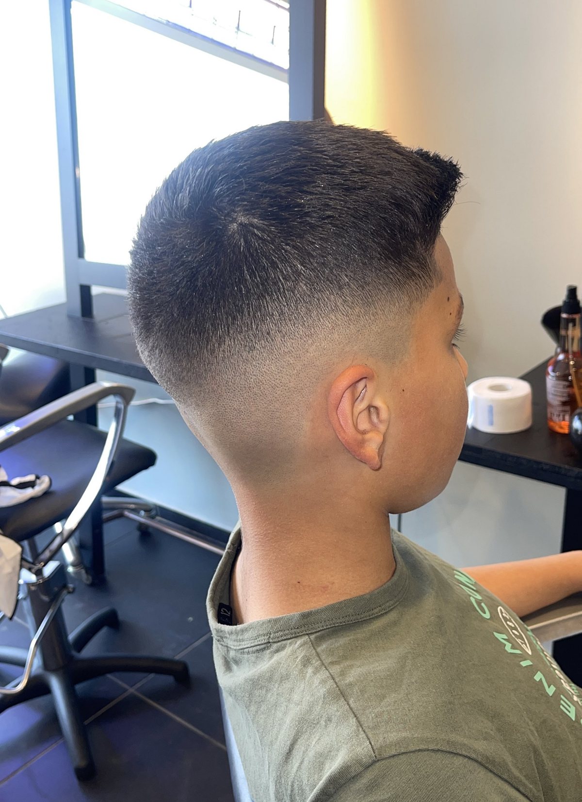 Jongen met een verse fade, van opzij gezien in de salon
